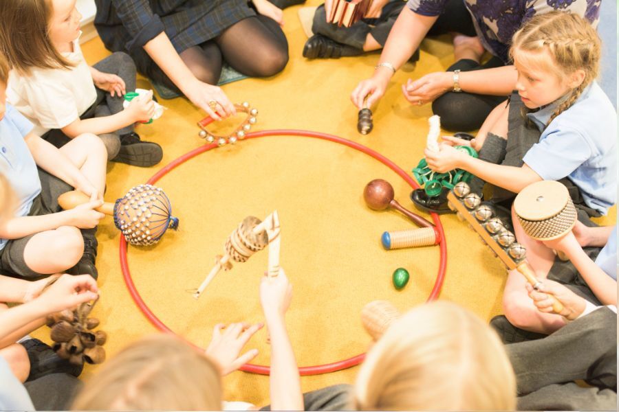 A group of primary school age children sat on the floor in a circle playing a game