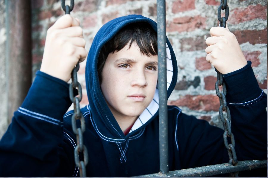 A young boy sat on a swing, looking serious or sad