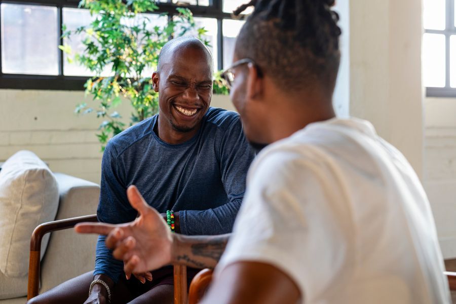 Two men, smiling and sat chatting to each other