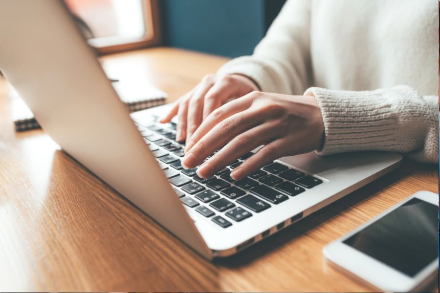 Photo shows someone's hands typing on a laptop