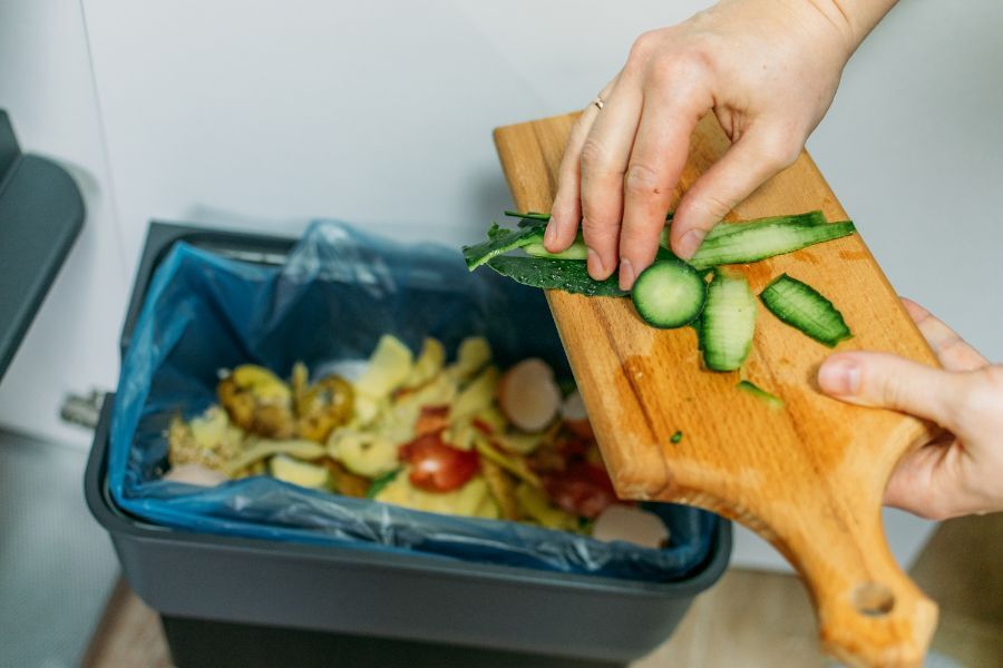 food waste being scraped into a kitchen caddy