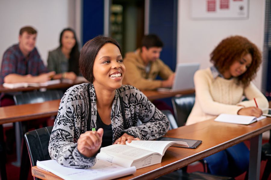 Students at college sat with their books in front of them looking ahead at their tutor