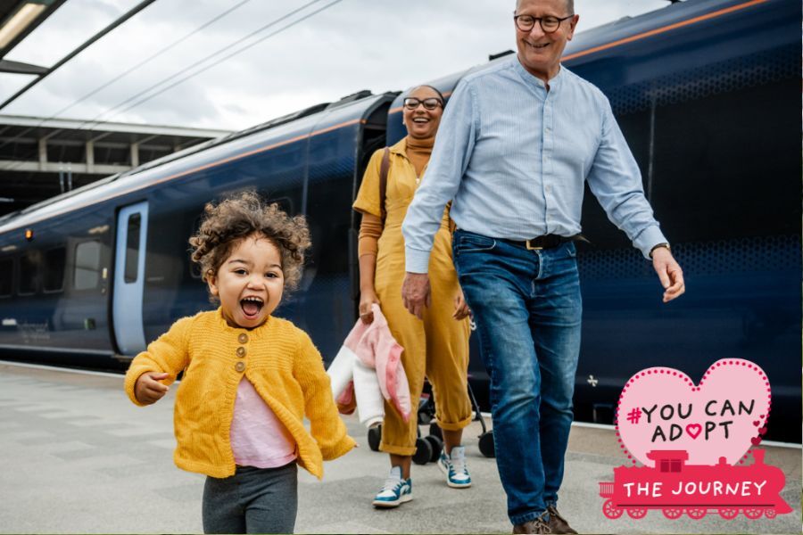 An adoptive family walking along a train station platform