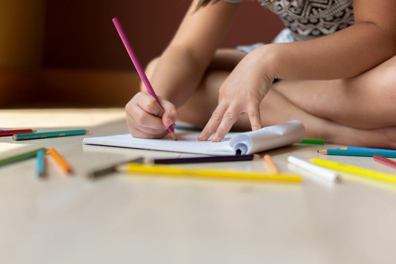 a child sitting on the floor with colouring pencils