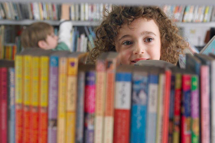 child peeping through books in a library