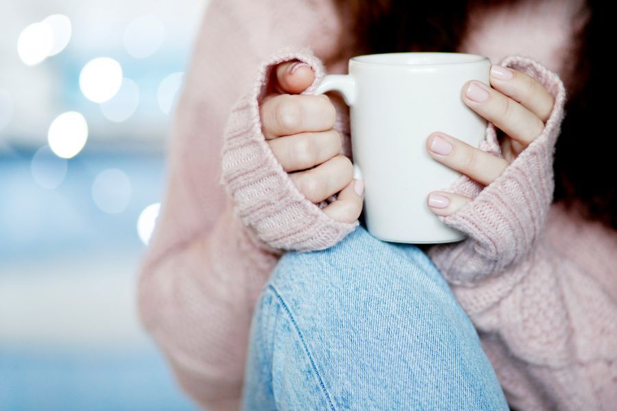 Woman holding mug of coffee with a woolly jumper on