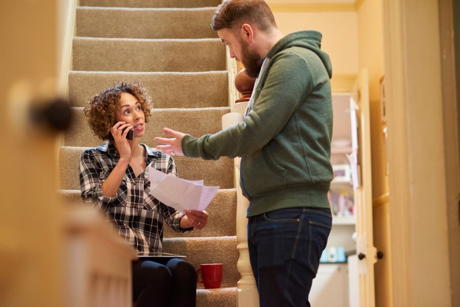 Woman on phone looking worried standing next to a man at home