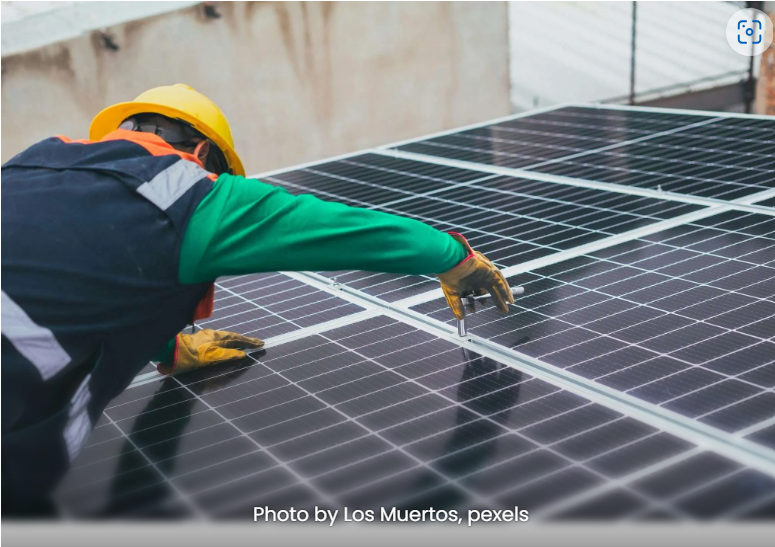 person installing a solar panel on a roof