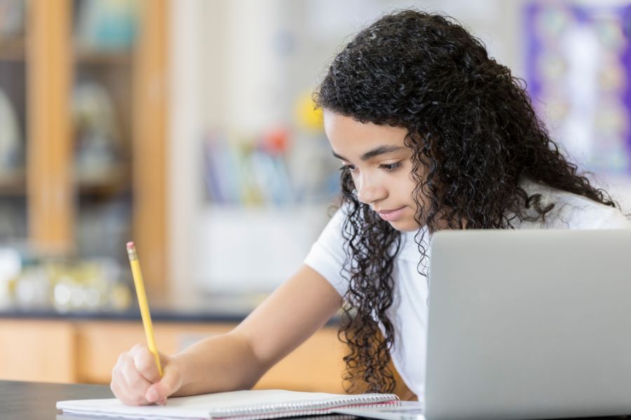 Young girl writing with laptop top