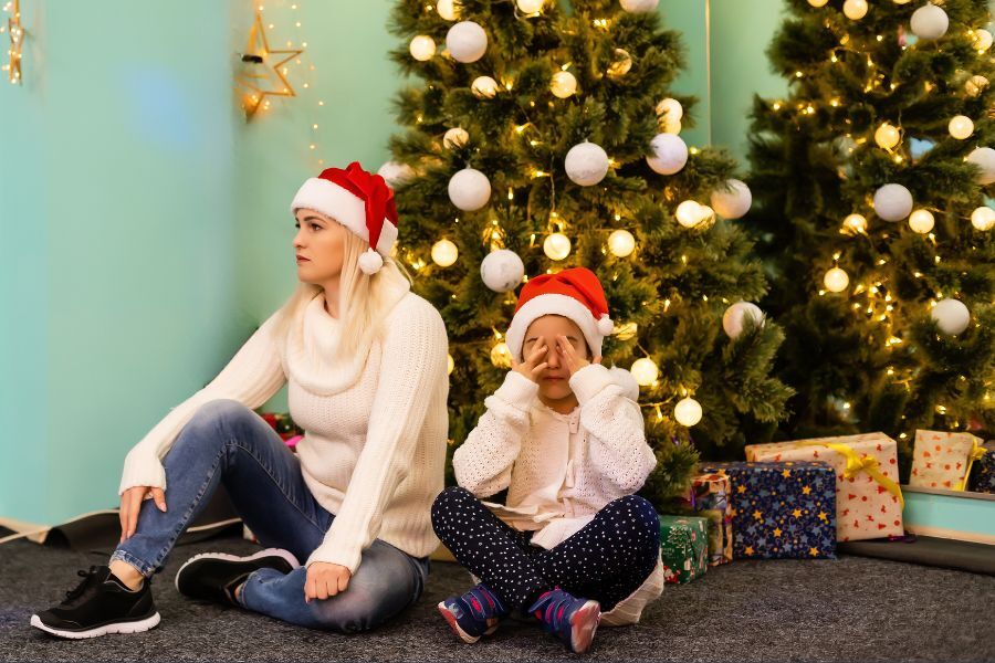 Mother and child sat by Christmas tree