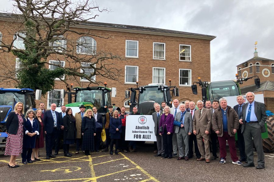 Councillors gathered outside county hall with farmers and tractors behind them