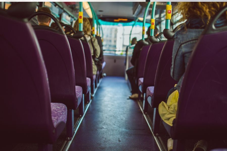 inside a bus, looking along the centre of the bus towards the front.  The backs of people's heads are in the photograph