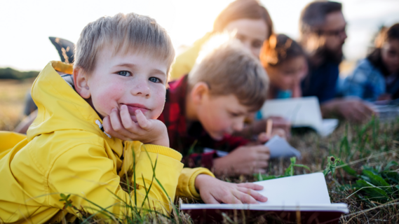 Child lying on grass with notepad