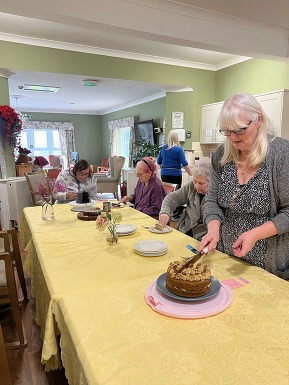 Person cutting a cake in a care home