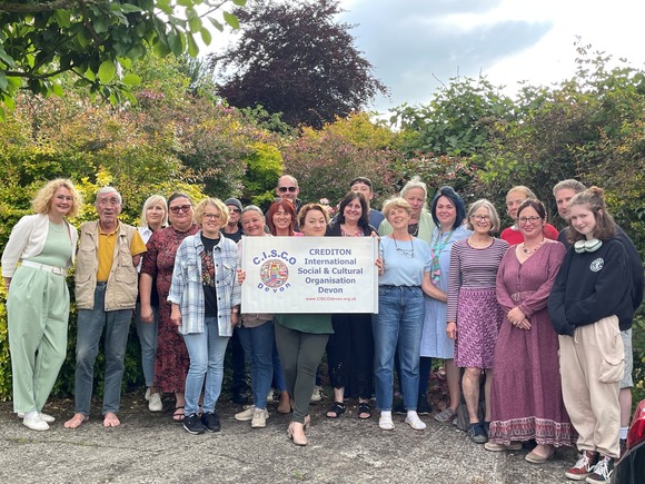 Group of people from Crediton International Social and Cultural Organisation standing outside in front of trees