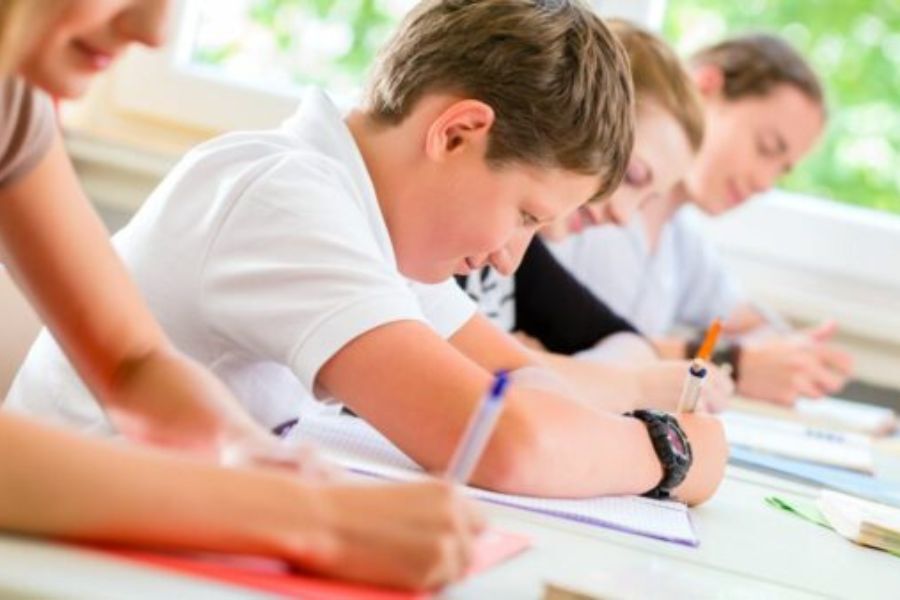 A row of school pupils in the classroom, working at their desks