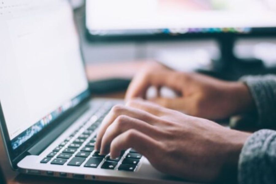 Hands typing on a laptop, on a desk.