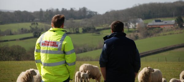 A farmer stood with a trading standards officer looking over fields