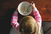 young girl eating a bowl of cereal with milk