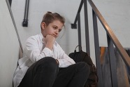 boy in secondary school uniform sitting on steps