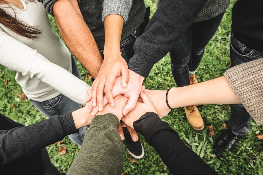 Teenagers holding hands in a circle. Only hands and wrists are showing.