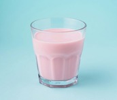 pink flavoured milk in glass on blue background