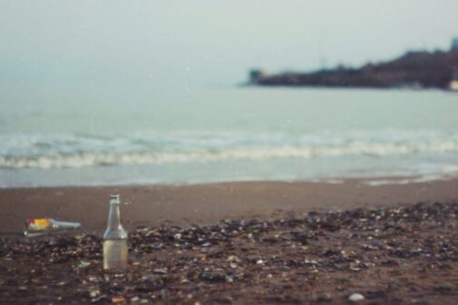 A pebbly beach by the sea and two empty bottles of beer on the pebbles