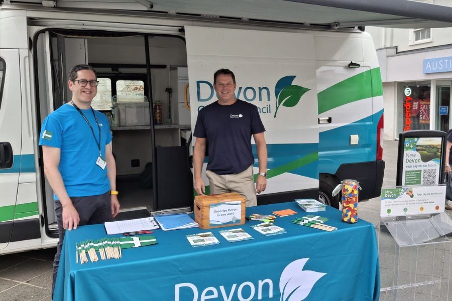 Two Devon County Council officers standing in front of a stand in Newton Abbot, ready to talk to local people