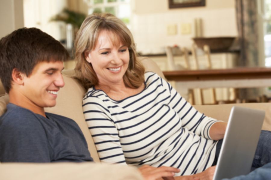 Young person looking at laptop with parent