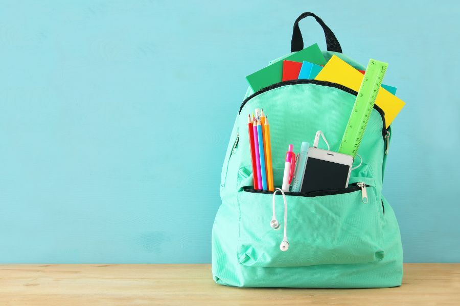 A school bag/ruck sack with stationery poking out of the top of the bag