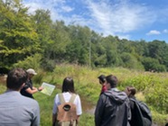 Group of people stood in a beaver created wetland looking at a map