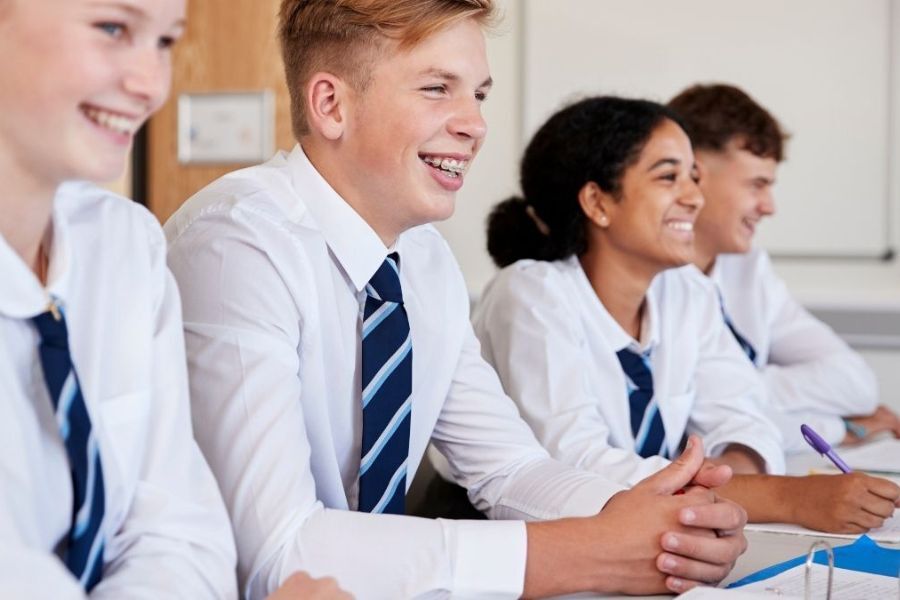 Teenage pupils sat in class, smiling