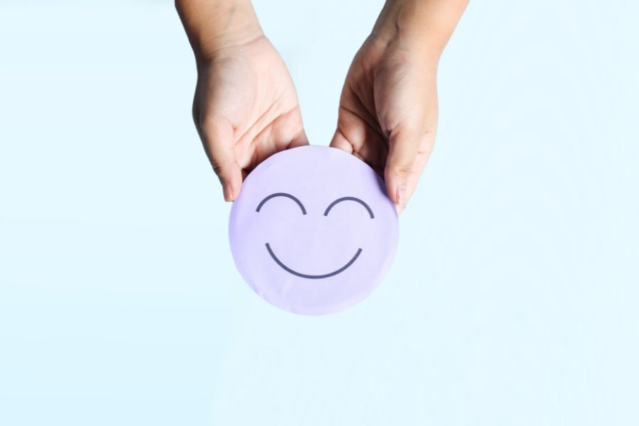 image shows a pair of hands holding a disk. The disk has a smiley face on it.