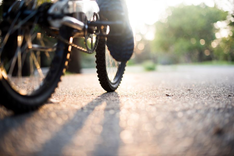 A bike, being ridden along  a road. Photo is a close up shot of the bike's wheels on the road.
