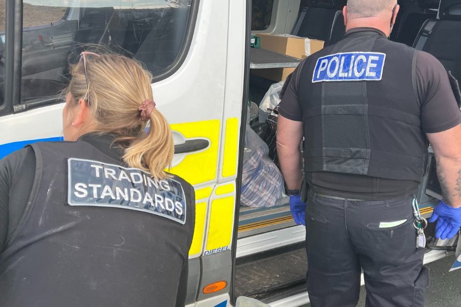 Trading Standards Officer and Police Officer putting counterfeit products into a police van
