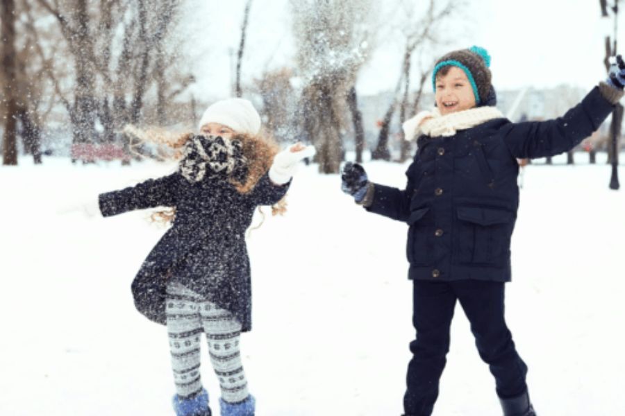 Two young children having fun playing in the snow