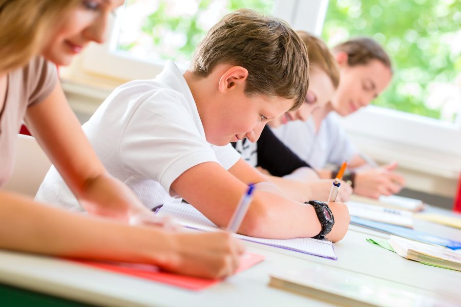 A row of school children sat in lessons, working at their desks