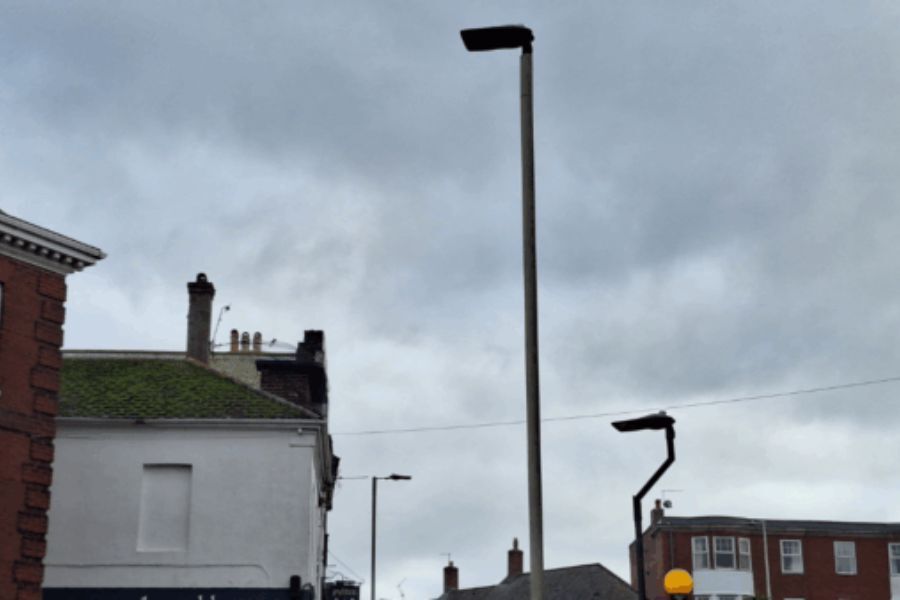 A street light, in a street, with residential houses adjacent