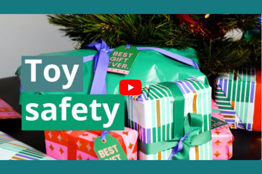 A Christmas tree with presents underneath and toy safety written and a video play button.