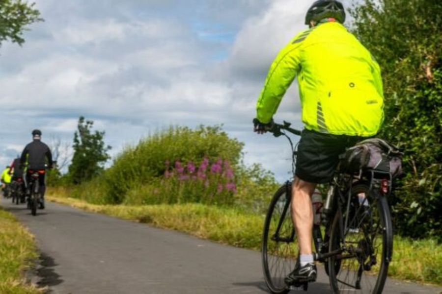 Cyclist wearing high visibility clothing and helmet cycling on a cycle path