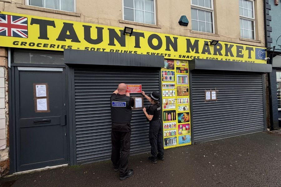 The exterior of the Taunton Market shop, with Police and Trading Standards officers putting up a closure notice