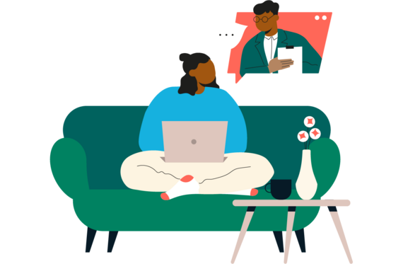 Person sitting on a green sofa with a laptop. A table sits in front with flowers and a mug on it. 