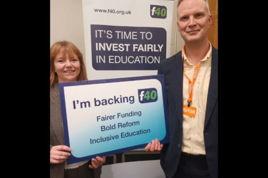 Two councillors stand with an f40 banner, holding a sign supporting fairer funding and inclusive education.