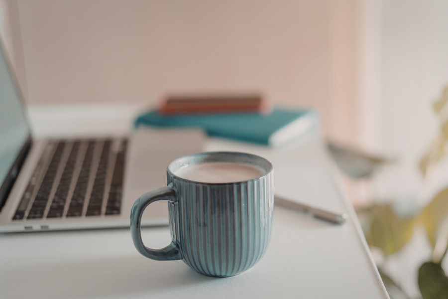 Laptop, notebook and mug on a desk, suggesting a calm home setting for online learning.