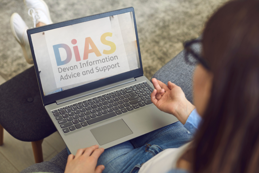 Person using a laptop displaying the DiAS Devon Information Advice and Support logo