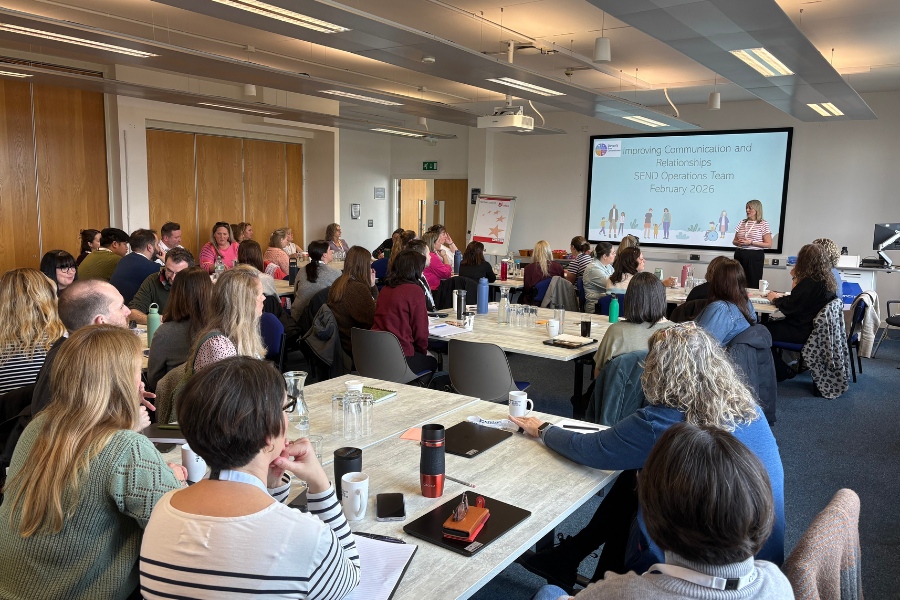 A large group of people seated in a training room facing a presentation screen titled “Improving Communication and Relationships.”