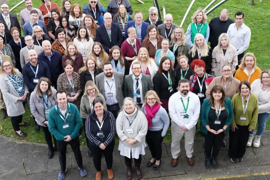 A large group of people stood outside, looking up at the camera