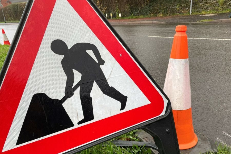 A road works sign and traffic cone in the road