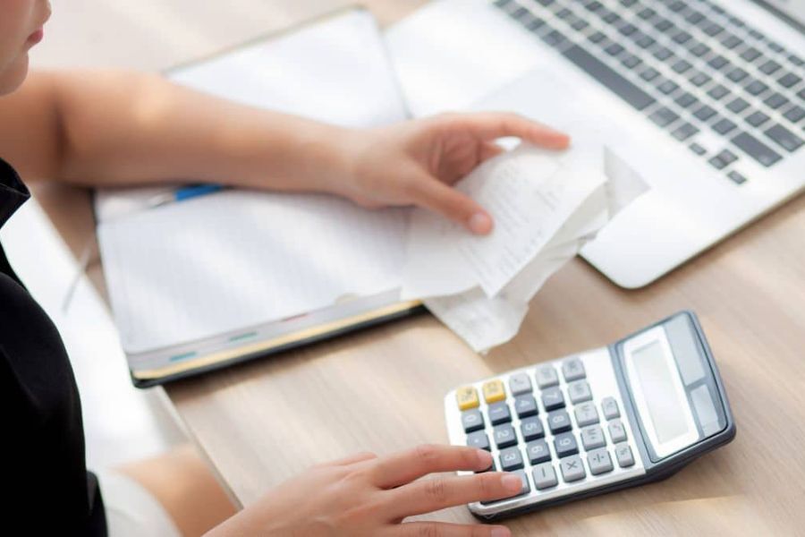 A person using a calculator while looking at their shopping receipt