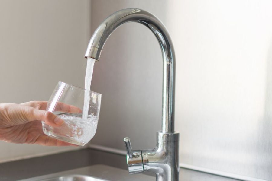 A person filling a glass with water from a tap